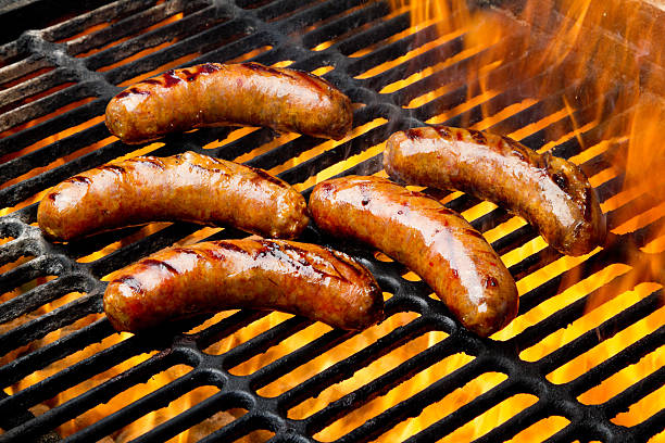 bratwurst-or-hot-dogs-on-grill-with-flames-picture-id168433704